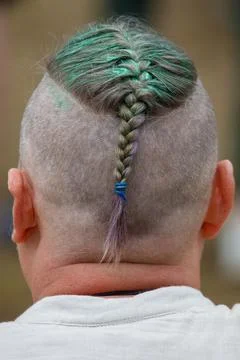 Back view of a person with a shaved head. Single green braided hair strand .. Stock Photos
