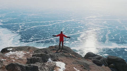 Back view of person standing on edge of cliff raising hands. Amazing inspiring Vídeo Stock 151860389