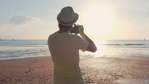 Back view of a photographer in a hat taking a photo of sunset Stock Footage 139693839