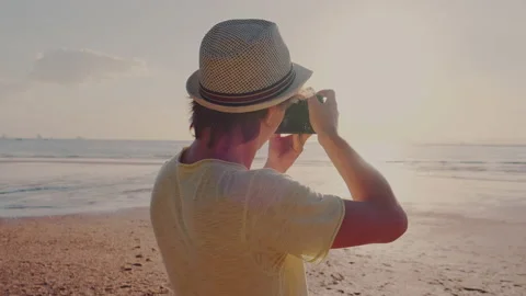 Back view of a photographer in a hat taking a photo of sunset Stock Footage 139852185