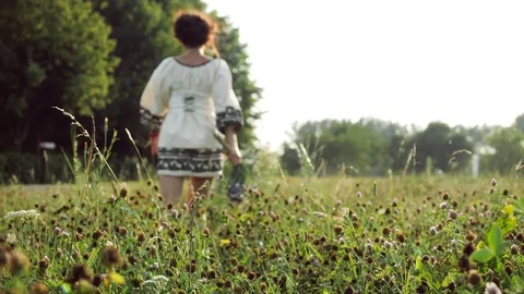 Back view. Pink clover on the background of a running girl on a meadow Stock Footage 81000191