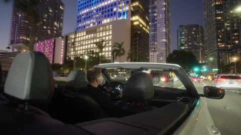 Back View POV of Man Driving White Convertible Sports Car at Night in Miami Stock Footage 317694843