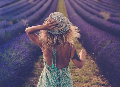 Back view of pretty babe in boho elegant blue dress walk in lavender fields w Stock Photos