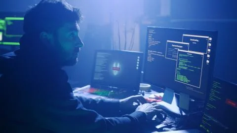Back view of programmer coding technologies on computer in smoky office at night Stock Photos