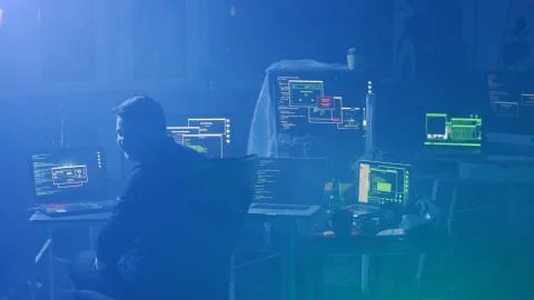 Back view of programmer coding technologies on computer in smoky office at night Stock Photos