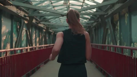 Back view of the receding figure of a beautiful girl running across the bridge Stock Footage 195080784