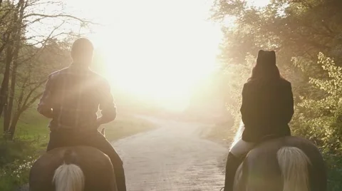 Back view of romantic couple of jockeys riding horses on sunset. Countryside Stock Footage 66036688
