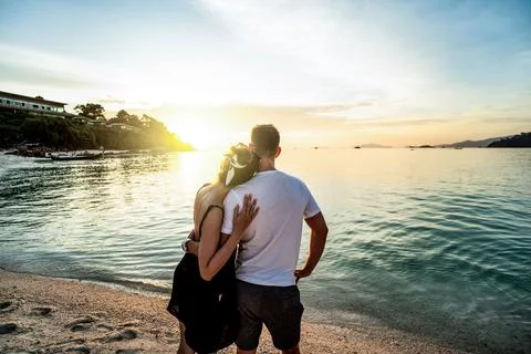 Back view of romantic couple looking at the sunset, relaxing at the beach, .. Fotos de archivo
