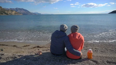 Back view of romantic couple sitting on the beach and look at the sea Stock Footage 86118692
