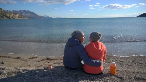 Back view of romantic couple sitting on the beach and look at the sea Stock Footage 86123610