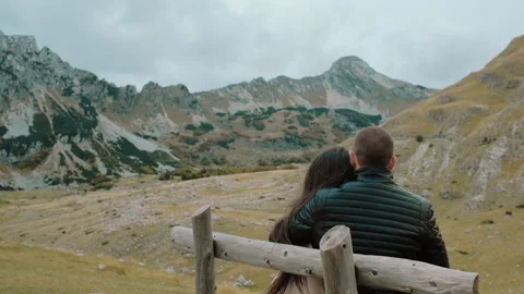 Back view romantic couple sitting on bench and looking at  the mountains Stock Footage 130589515