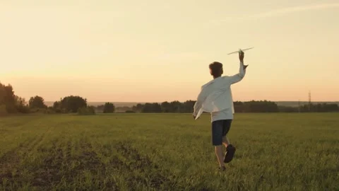 Back view of a running boy in a white shirt on a country road in a summer sunny Stock Footage 246426209