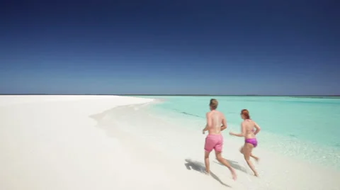 Back view of running couple on sandy beach Stock Footage 1018193
