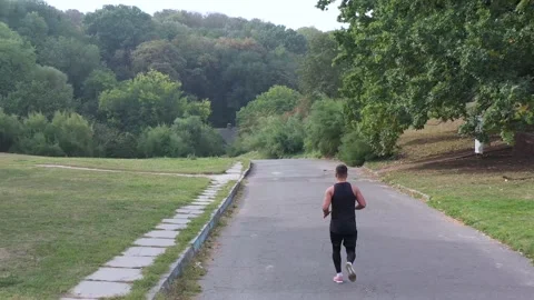 Back view of running man in summer park. Active athlete training cardio Stock Footage 141056737