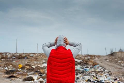 Back view of scared human with hands on head in red jacket, looking at field. Stock Photos