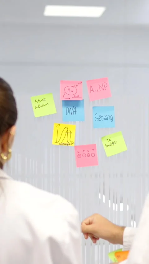 Back view of scientists sticking notes on wall Stock Footage 256940366