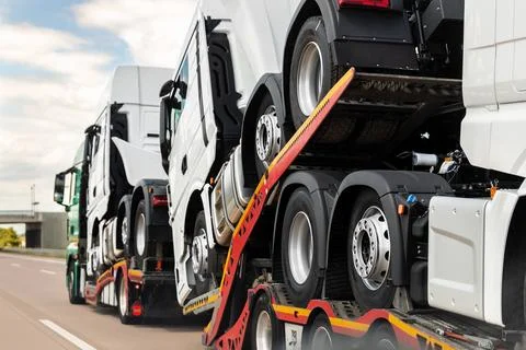 Back view of semi-trailer flatbed vehicle deliverying many new electric trucks 스톡 사진