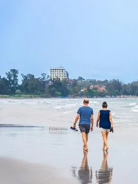 Back view of senior lovers walking together on beach. Portrait elderly coup.. Stock Photos