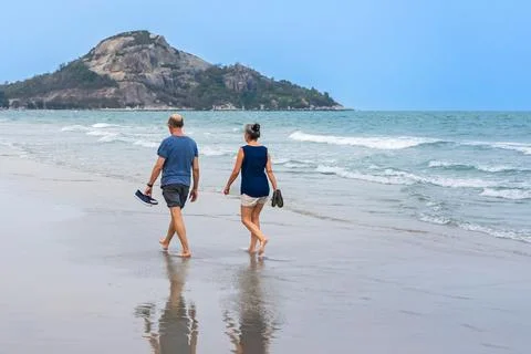 Back view of senior lovers walking together on beach. Portrait elderly coup.. Stock Photos