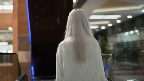 Back view shopper entering descending moving walkway in mall Vidéo 316832845