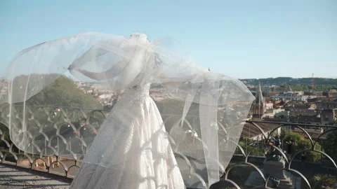Back view shot of gorgeous bride in lace wedding dress waving her long veil in Video stock 226142367