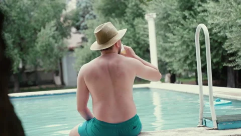 Back view shot of man in straw hat sitting on pool side, enjoying amazing view Stock Footage 296803519