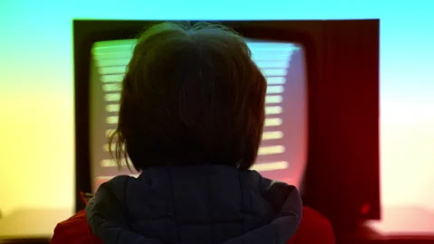 Back view shot of middle-aged woman sitting in front of retro television against Stock Footage 231402047
