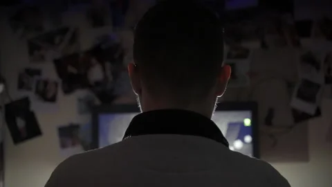 Back view shot of unrecognizable man sitting in dark room with blinking lights 스톡 동영상 143854205