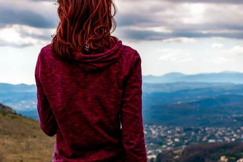 A back view shot of an unrecognizable  young redheaded woman standing enjoyin Stock Photos