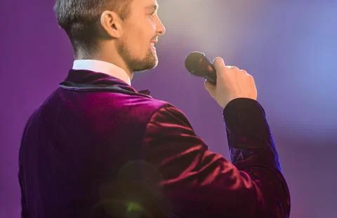 Back view showman singer with microphone on stage in spotlight, velvet suit Stock Photos