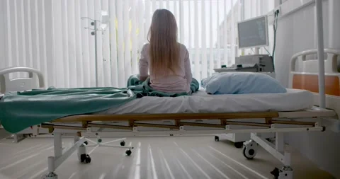 Back view of sick child sitting in bed alone in hospital room Stock Footage 148988676