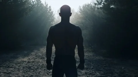Back view of silhouette Muscular man With Naked Torso standing in front of the Видео 125863353
