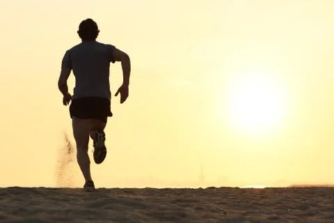 Back view silhouette of a runner man running on the beach Stock-Fotos