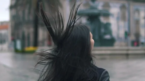 Back view of slender young brunette woman wearing coat walking down street on Stock Footage 93377270