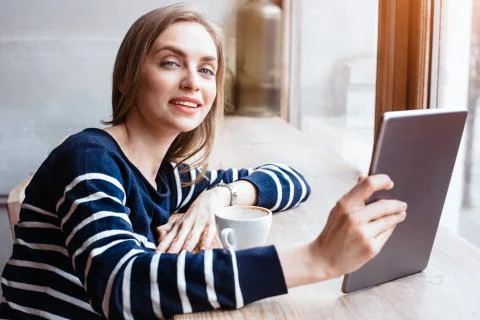 Back view smiling beautiful young woman read magazine with digital tablet near Stock Photos