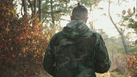 Back view of soldier walk to sunset in forest with rifle on shoulder Stock Footage 131715014