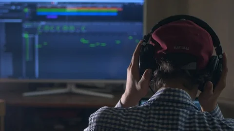 Back view of sound engineer in snapback and holding headphones on head monito Stock Footage 96171243