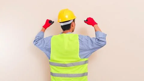 Back view of Southeast Asian construction worker in hard hat and safety ves.. Stock Photos