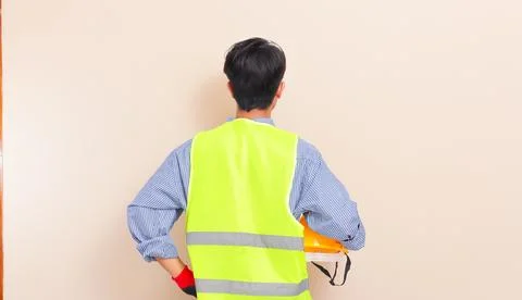 Back view of Southeast Asian construction worker in yellow hard hat and saf.. Stock Photos