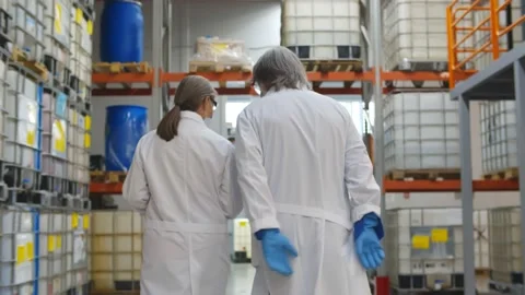 Back view of specialists in lab coat and gloves walking in industrial warehouse Stock Footage 143555818