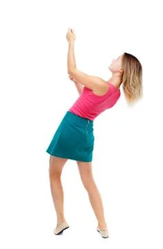 Back view of standing girl pulling a rope from the top or cling Stock Photos