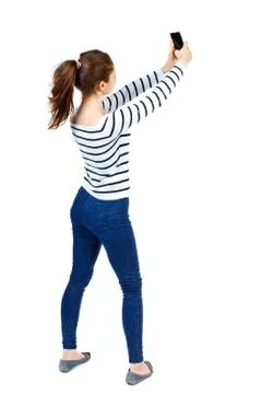 Back view of standing young beautiful  woman  using a mobile pho Foto stock