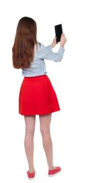 Back view of standing young beautiful  woman  using a mobile pho Foto stock