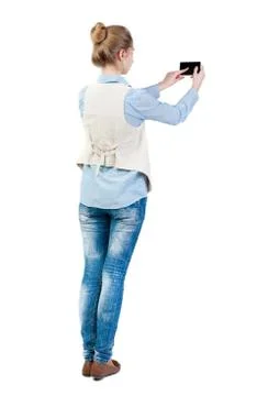 Back view of standing young beautiful  woman  in vest and using Stock Photos