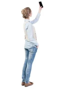 Back view of standing young beautiful  woman and using a mobile Stock Photos
