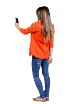 Back view of standing young beautiful  woman  using a mobile pho Foto stock