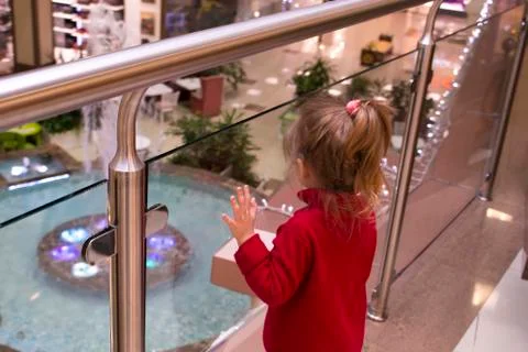 Back view of standing young beautiful girl in a red sweater in the shopping mall Stock Photos
