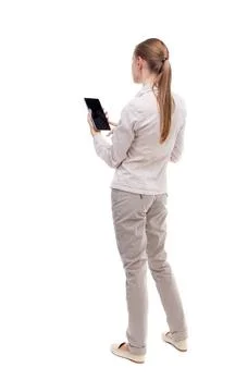 Back view of standing young beautiful girl with tablet computer back view ... Stock Photos