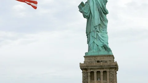 Back view of the statue of liberty with flag waving in foreground. Stock Footage 118604666