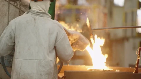 Back View of Steel Foundry Employee Pouring Bright Liquid Steel Видео 345002016